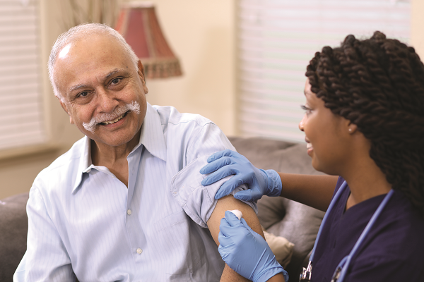 Nurse administering a smiling patient a vaccine